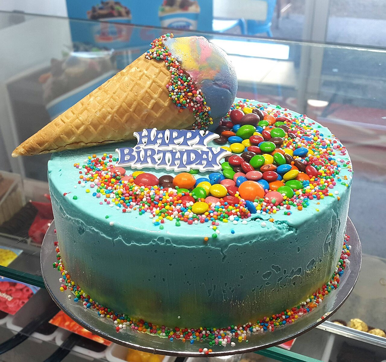 Colourful rainbow sprinkle ice cream cake with a waffle cone